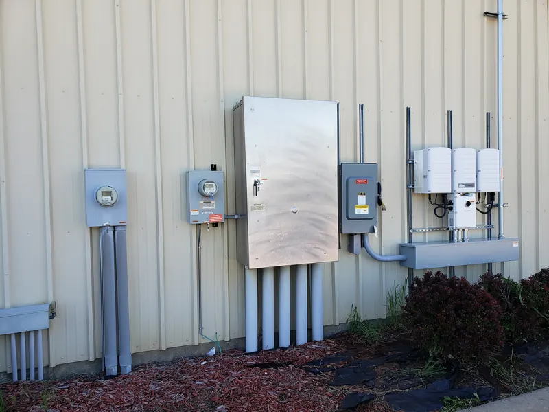 Electric meters, disconnect switches and inverters mounted on a commercial building wall