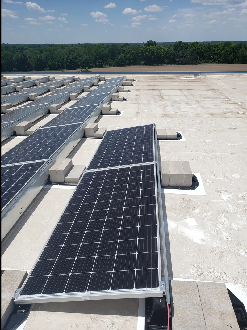 Rows of solar panels on ballasted racks along the edge of a flat commercial roof