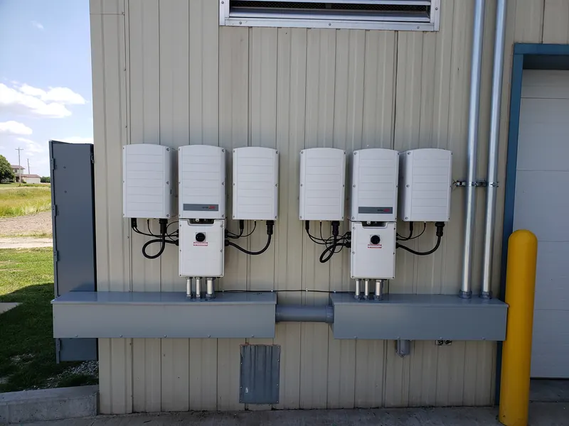 Six solar inverters mounted in two groups on a commercial building wall