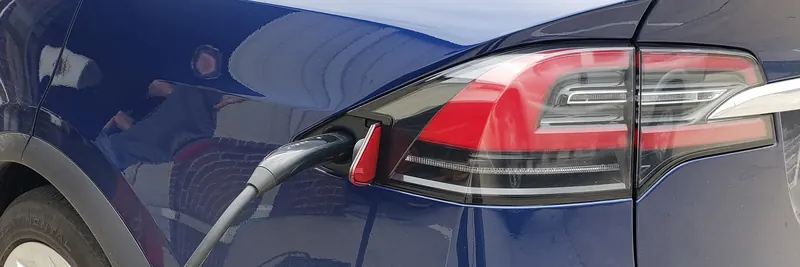 Charging cable plugged into the port of a dark blue electric car