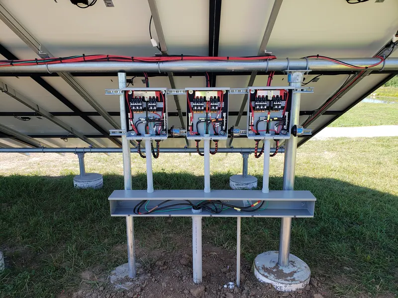 Combiner boxes and wiring mounted under a ground-mounted solar array