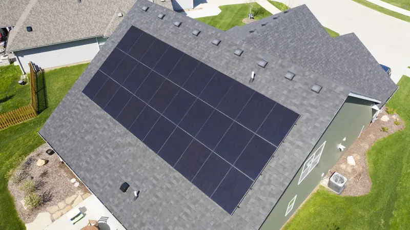 Aerial view of a green two-story home with a large solar array